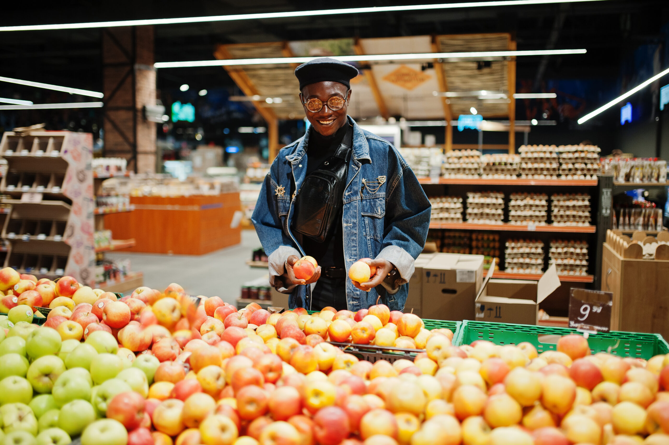 stylish casual african american man jeans jacket black beret checking apple fruits organic section supermarket scaled